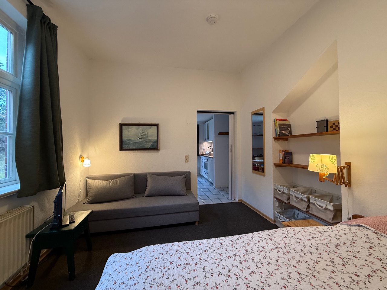 Fewo Wattwurm: Wohn-/Schlafzimmer mit (Schlaf-)Sofa sowie Sortierboxen für Klamotten u. ä. im Wandregal